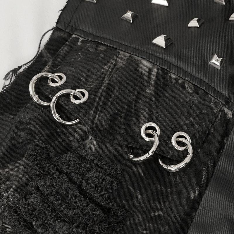 Close-up of gothic mesh rivets and metal rings on a punk rock waistcoat pocket with distressed black fabric.