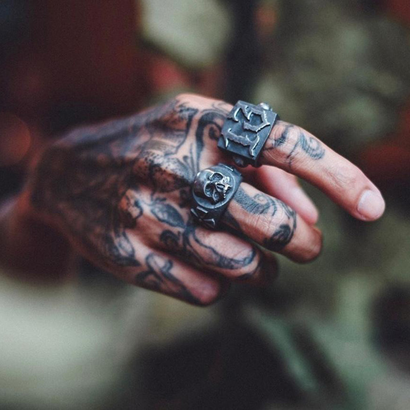 Close-up of a tattooed hand wearing a retro gothic ring with number 13 and a skull design, perfect for punk rock style.