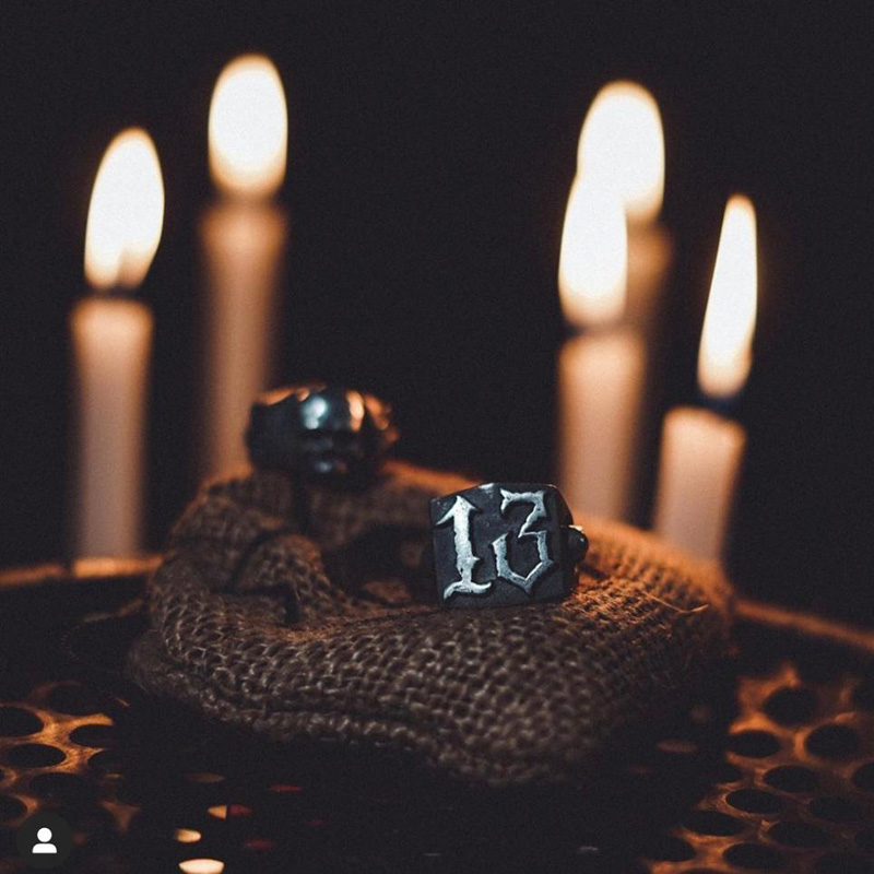 Punk rock retro gothic ring featuring the number 13, set against candles in a dark atmosphere.