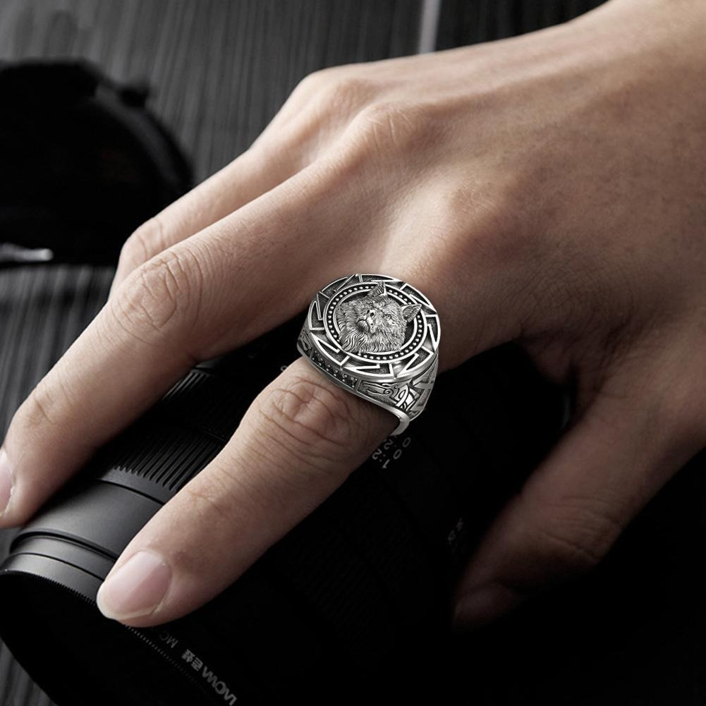 Close-up of a stylish man's hand wearing a punk rock wolf head ring on a camera lens.