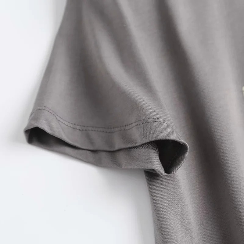Close-up of the sleeve of a punk rock style women's O neck T-shirt in soft grey cotton fabric.