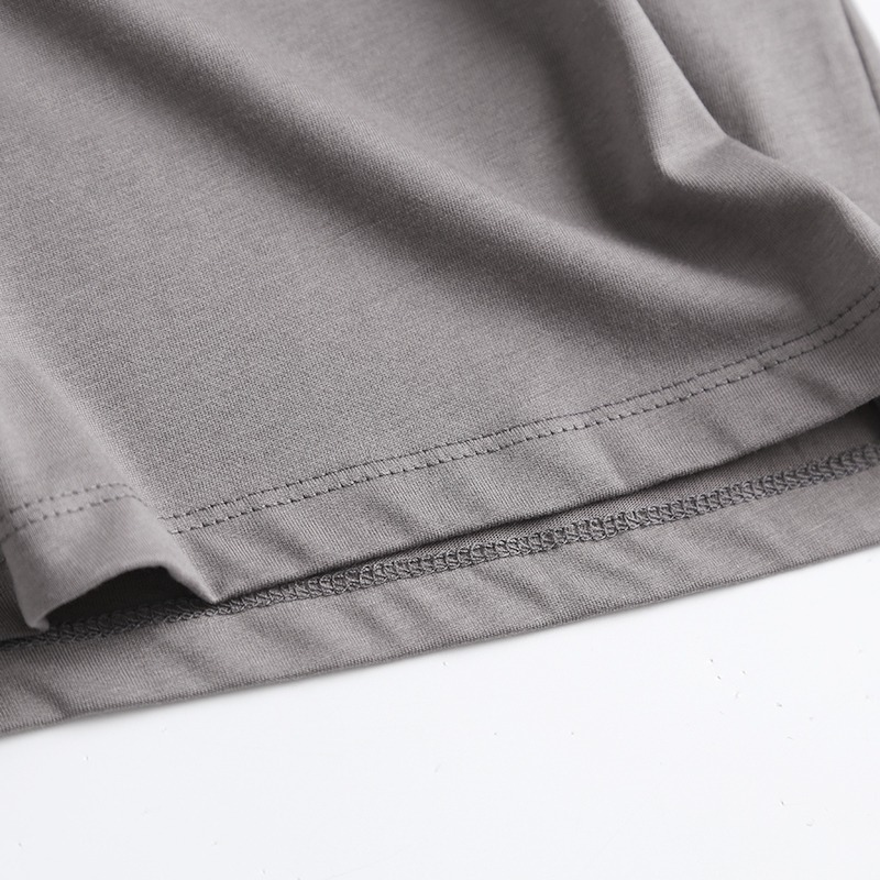 Close-up of a grey cotton t-shirt hem, showcasing fabric texture and stitching details, perfect for casual punk rock outfits.