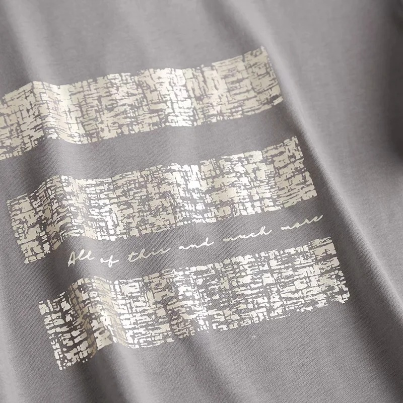 Close-up of a grey punk rock style women's cotton T-shirt featuring a stylish print with text and textures.