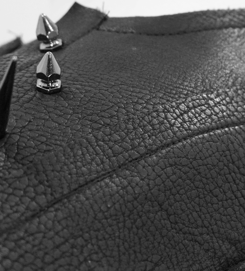 Close-up of leather texture featuring silver spikes on a black punk sleeveless top.