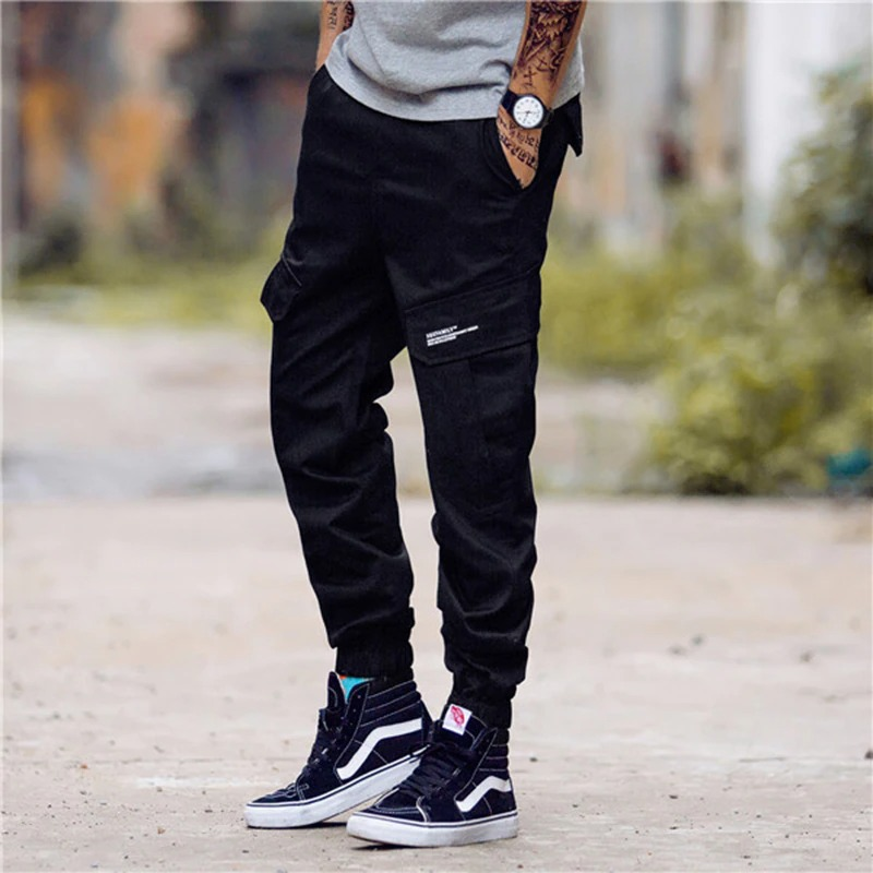 Men's punk style black cargo pants with pockets, paired with stylish sneakers for a trendy look.