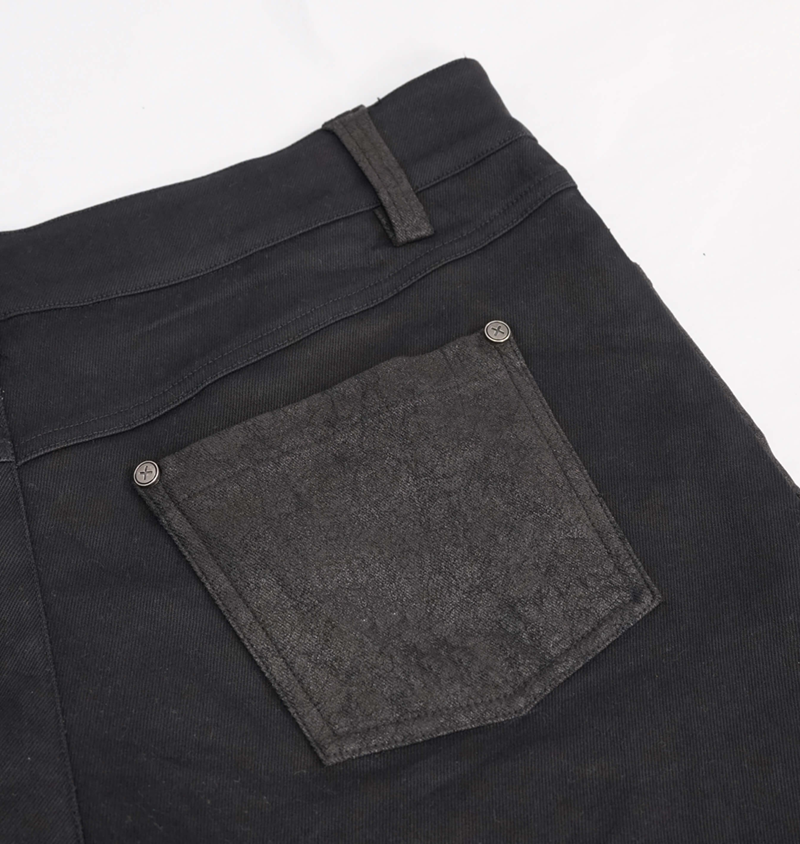 Close-up of the back pocket on black punk style men's jeans with faux leather trim and stylish details.