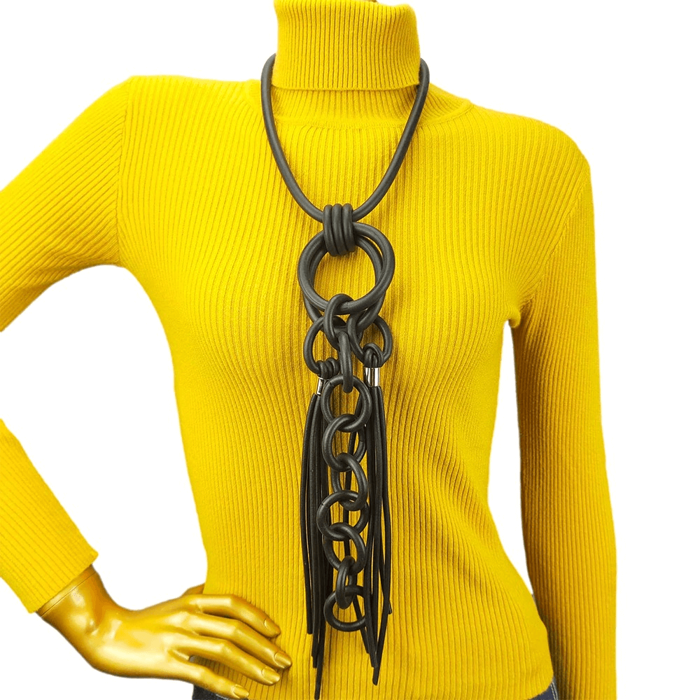Punk style handmade black rubber necklace on a model wearing a yellow turtleneck, showcasing unique design and statement fashion.