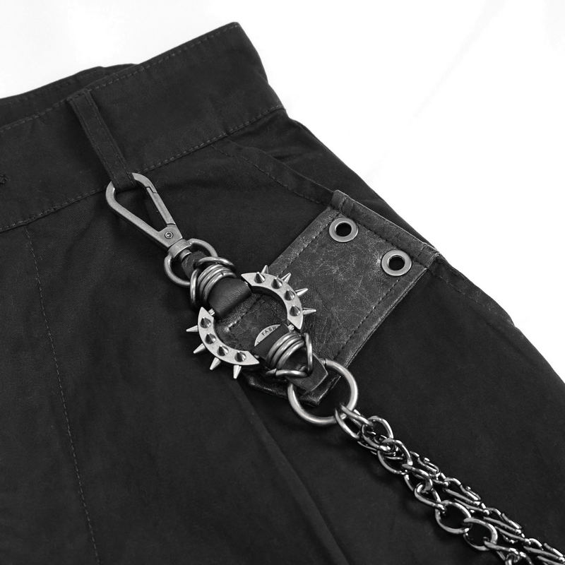 Close-up of punk style women's black cargo pants featuring a detachable chain and spiked accessory.