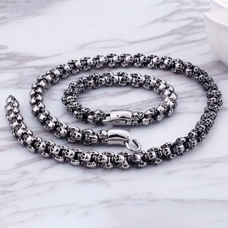 Punk style stainless steel skull bracelet and necklace set on marble background, perfect for edgy fashion lovers.