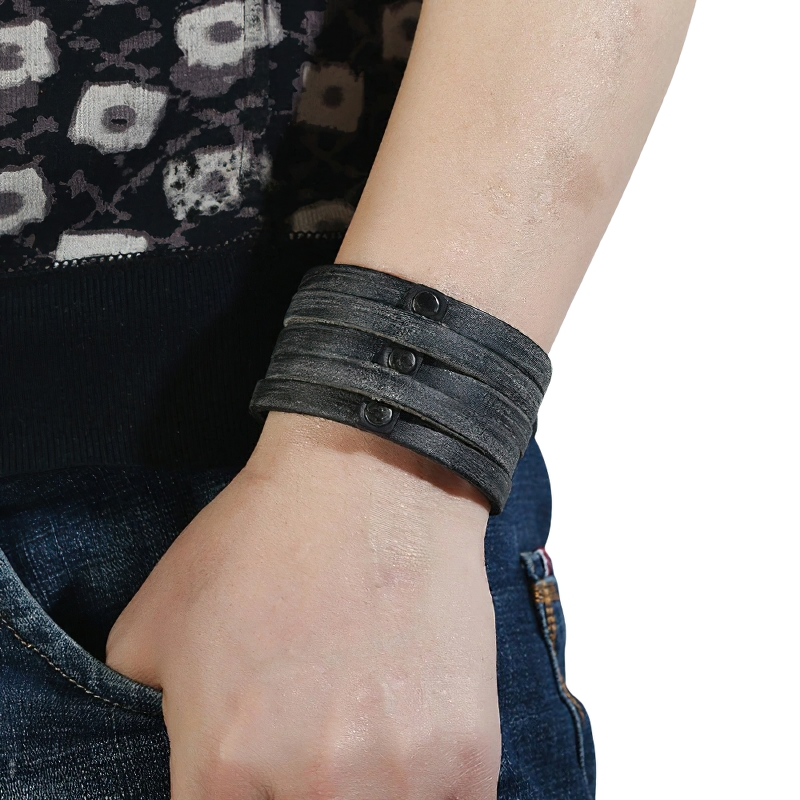 Wide leather punk bracelet with black rivets on a person's wrist, perfect unisex fashion accessory.