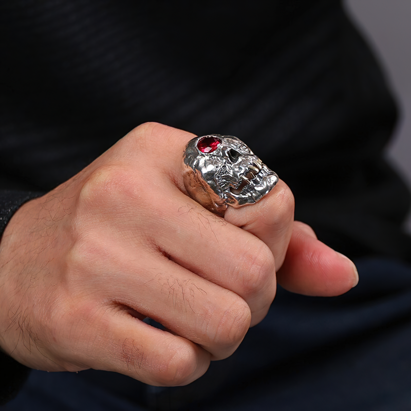 Unisex stainless steel red crystal skull ring worn on a hand, showcasing gothic-inspired jewelry for men and women.