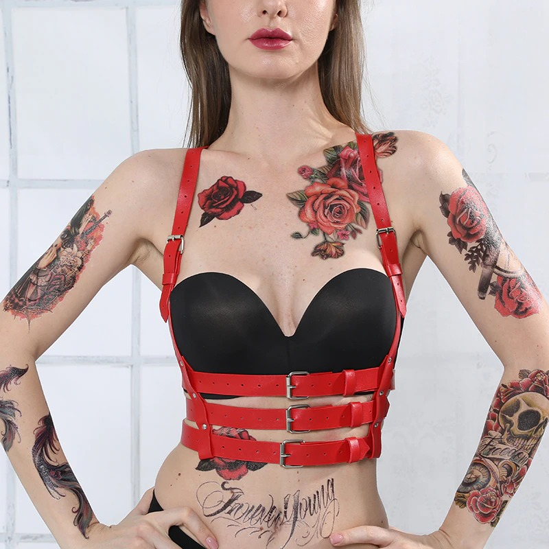 Red gothic PU leather harness with silver fittings, enhancing curves and style, showcased on a tattooed model.
