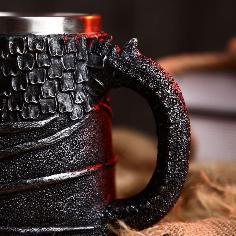Close-up of a vintage resin and stainless steel beer mug with dragon detail and textured handle.