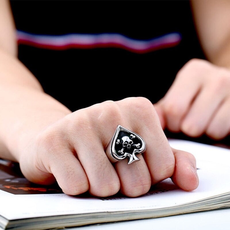 Close-up of a person wearing a Retro Card Cross Skull Ring with spade design, showcasing rock style jewelry on their hand.