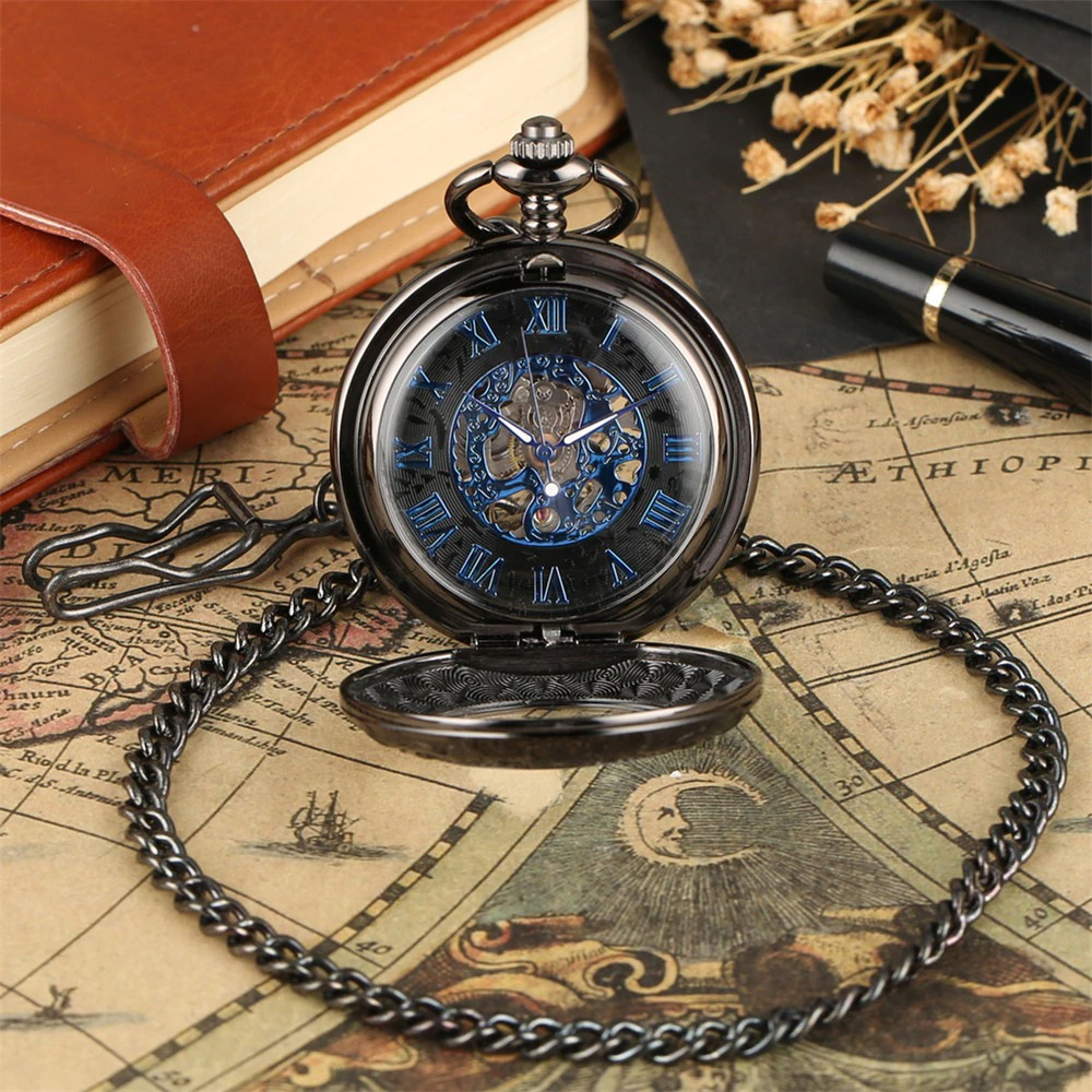 Retro mechanical pocket watch with blue Roman numerals and chic design, resting on a vintage map and leather notebook.