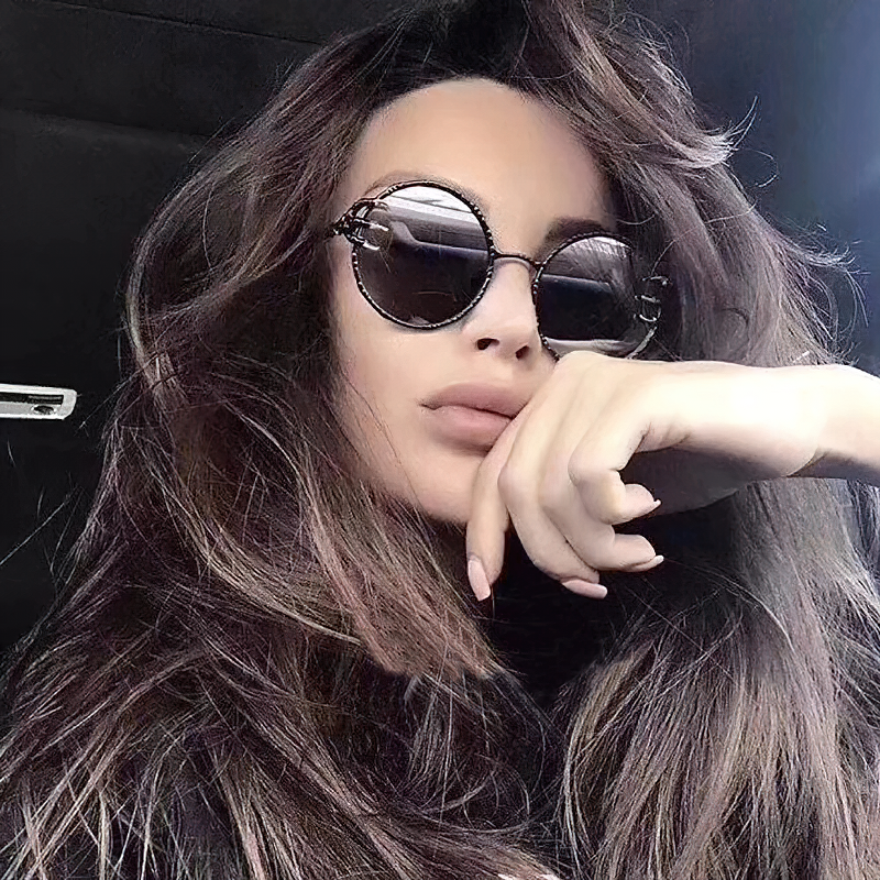 Fashionable woman showcasing Retro Skull Claw Round Sunglasses with a gothic flair and stylish metal frame.