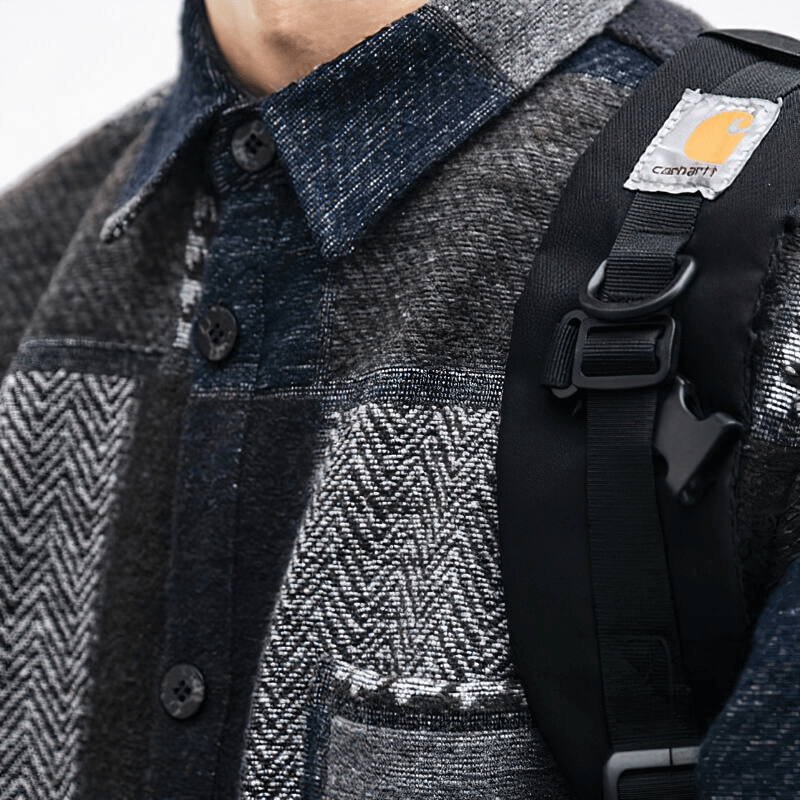 Close-up of a man's retro woolen plaid shirt with buttons and a black strap, showcasing stylish casual fashion.