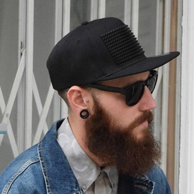 A stylish man wearing a rock style baseball cap with plastic spikes, showcasing a modern flat-brimmed snapback design.