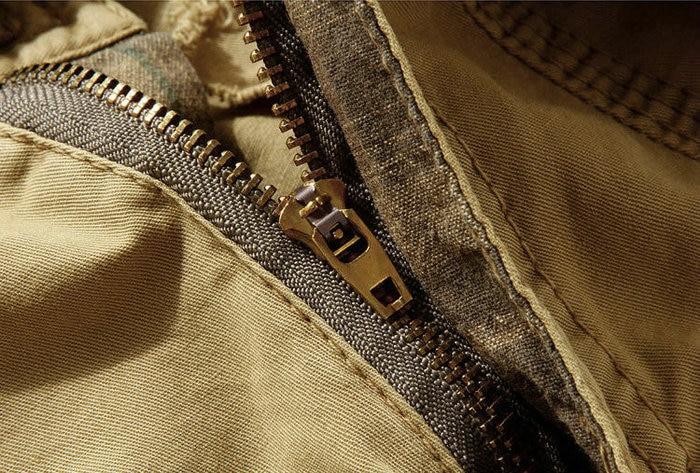 Close-up of a sturdy zipper on loose camouflage cargo shorts for men.