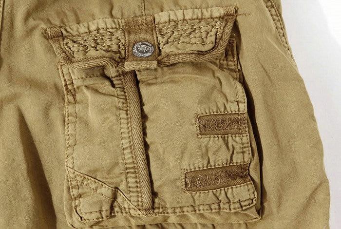 Close-up of loose camouflage cargo shorts pocket with decorative zipper and military-style details.