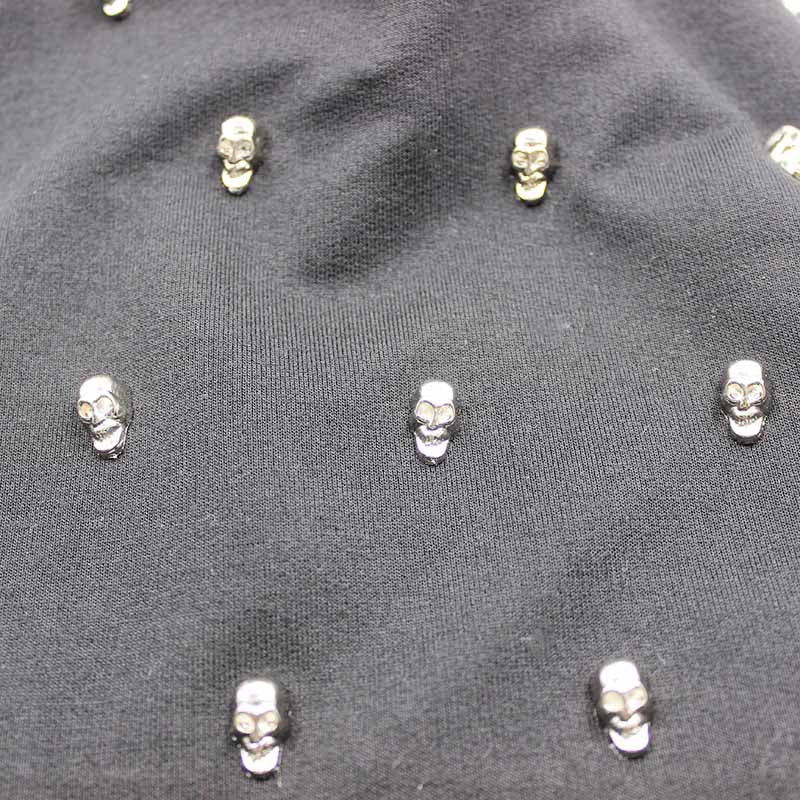 Close-up of black fabric with silver skull embellishments, perfect for punk rave outfits and gothic fashion.
