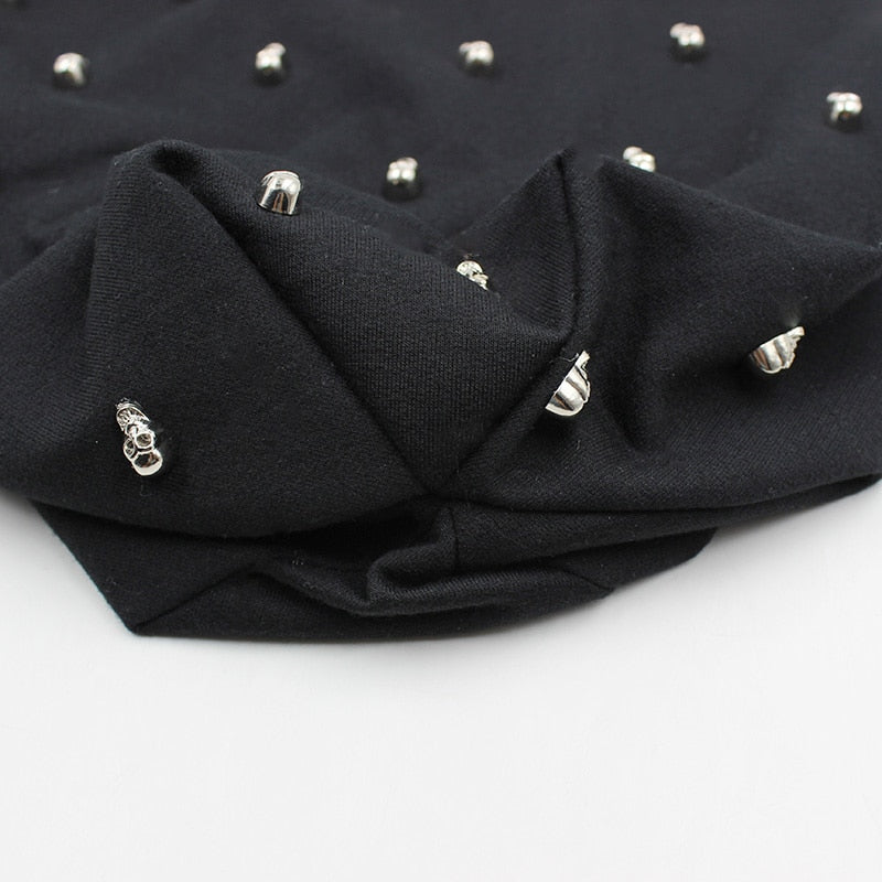 Close-up of a black rock style hat featuring silver skulls and hoops for a unique punk vibe.