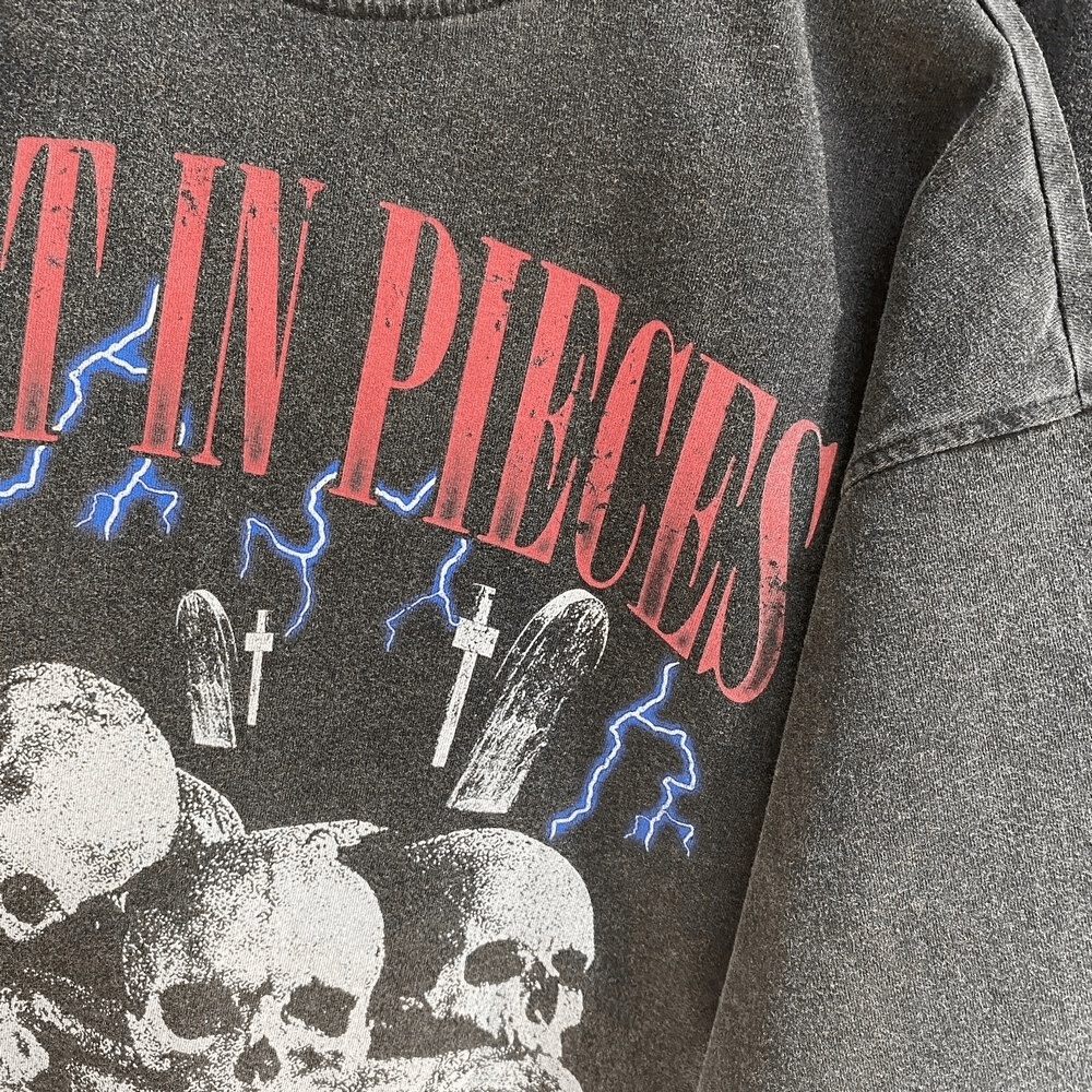 Close-up of a rock style oversized t-shirt featuring a bold 'Lost in Pieces' letter skull print and lightning graphics.