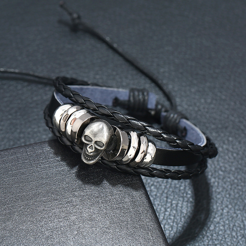 Stylish multi-layer leather bracelet with silver skull charm for men and women, perfect rock-style accessory.