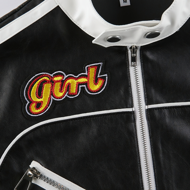 Close-up of black PU leather cropped jacket with colorful 'girl' patch and white accents for alternative streetwear fashion.