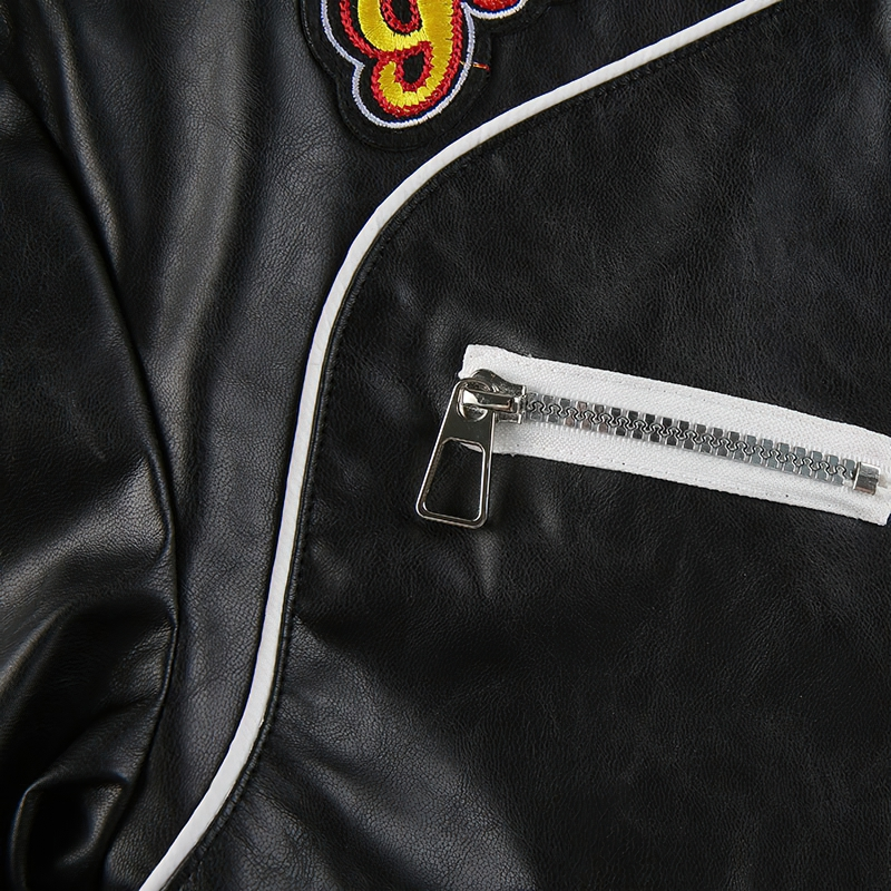 Close-up of a black PU leather jacket's patchwork design and zipper pocket, showcasing alternative fashion details.