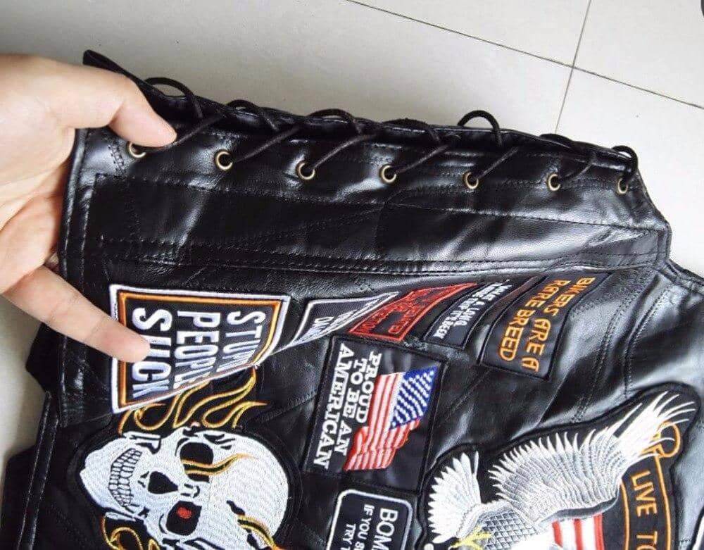 Close-up of a genuine leather biker vest with rock patches, showcasing skull and eagle designs.