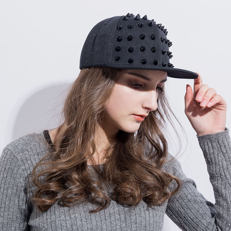 Stylish female model wearing a black rock style snapback hat with spikes, perfect for festivals and punk fashion.