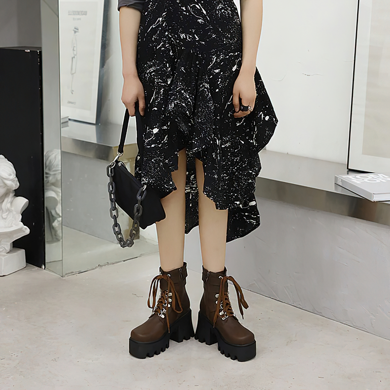 Trendy women lacing platform motorcycle boots in brown, paired with a stylish black dress in a chic setting.