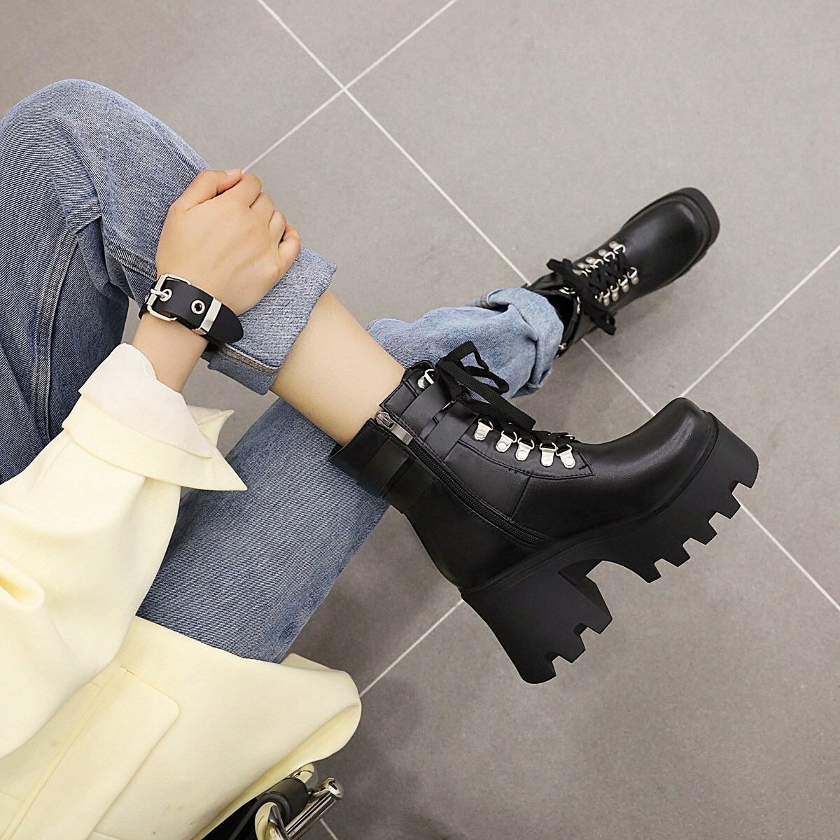 Black lacing motorcycle platform boots on heels paired with jeans, stylish rocker outfit for women.