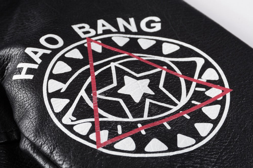 Close-up of a black leather patch featuring a bold graphic design with the text 'HAO BANG' and geometric shapes.