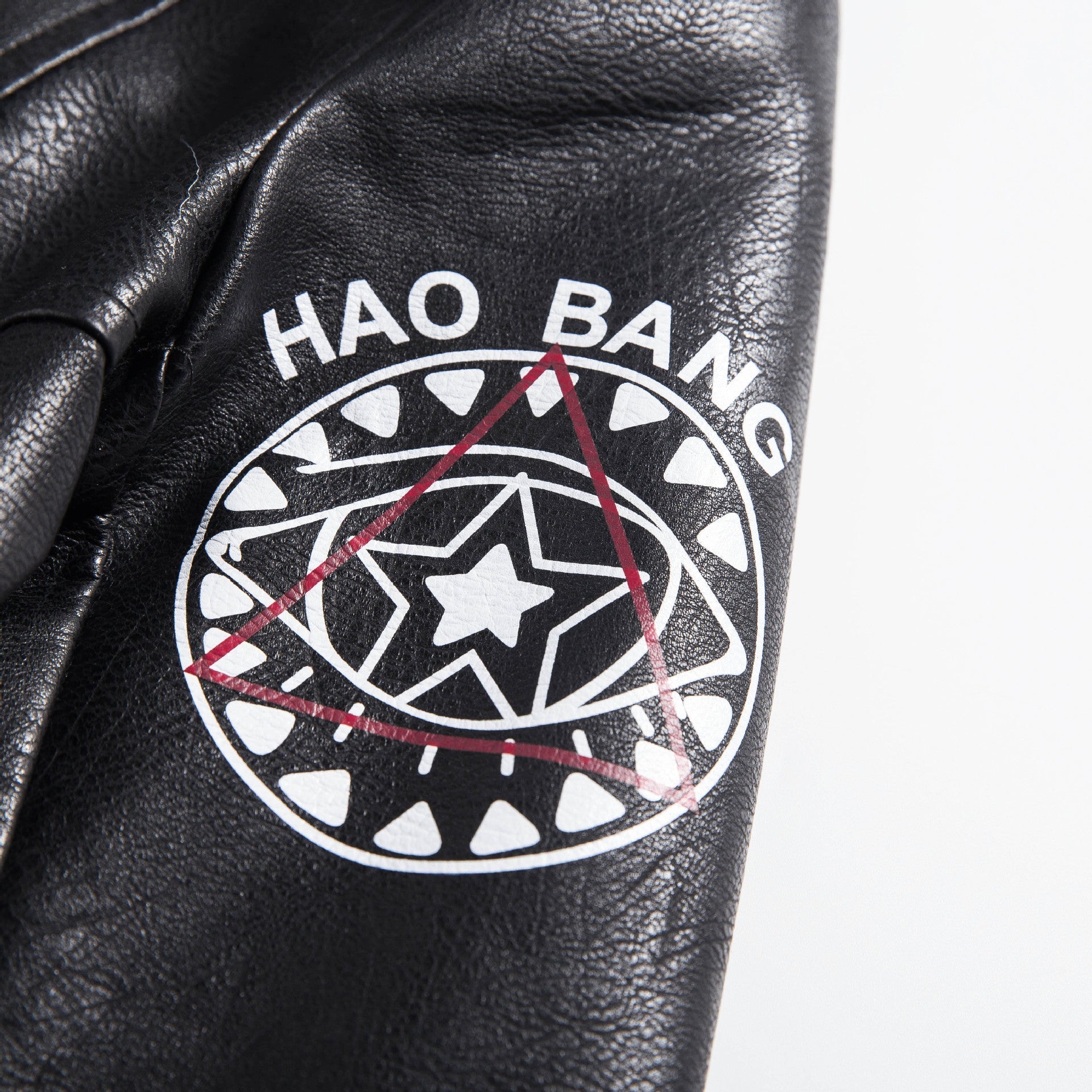 Close-up of a black faux leather jacket featuring a bold 'Hao Bang' logo and graphic design details.