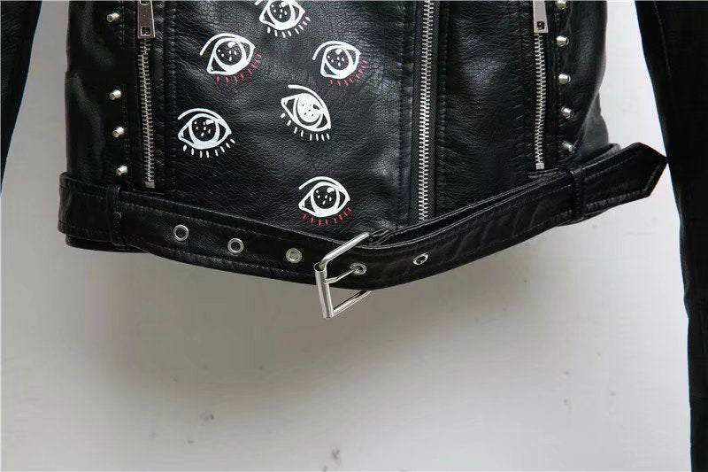 Close-up of a women's faux leather motorcycle jacket featuring 3D print eyes and studded detailing.