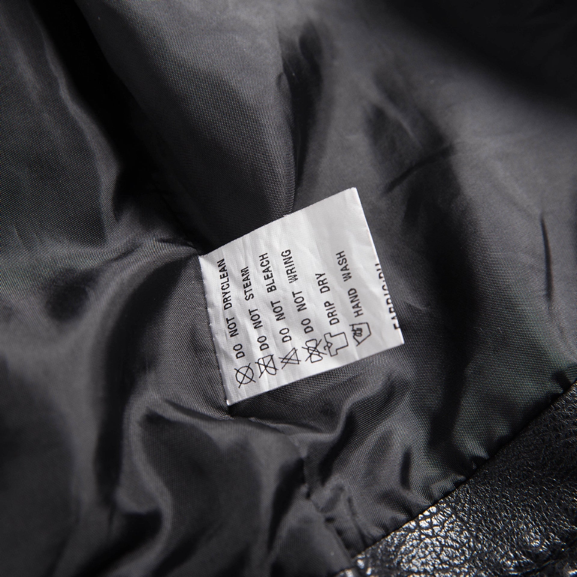 Care label inside a soft PU leather jacket indicating washing instructions and maintenance tips.
