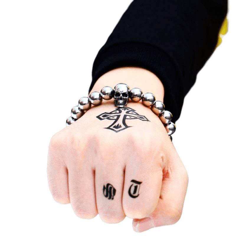 Round bead rock skull bracelet on a tattooed hand, showcasing a cool biker accessory in stainless steel.