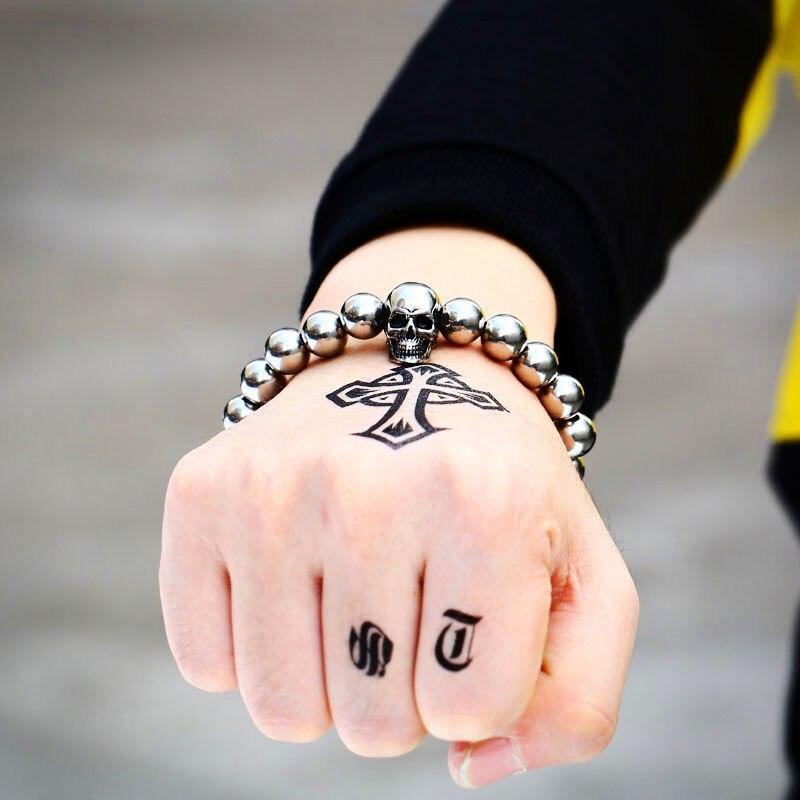 Stainless steel round bead skull bracelet worn on hand with tattoos, perfect for a trendy rock style.