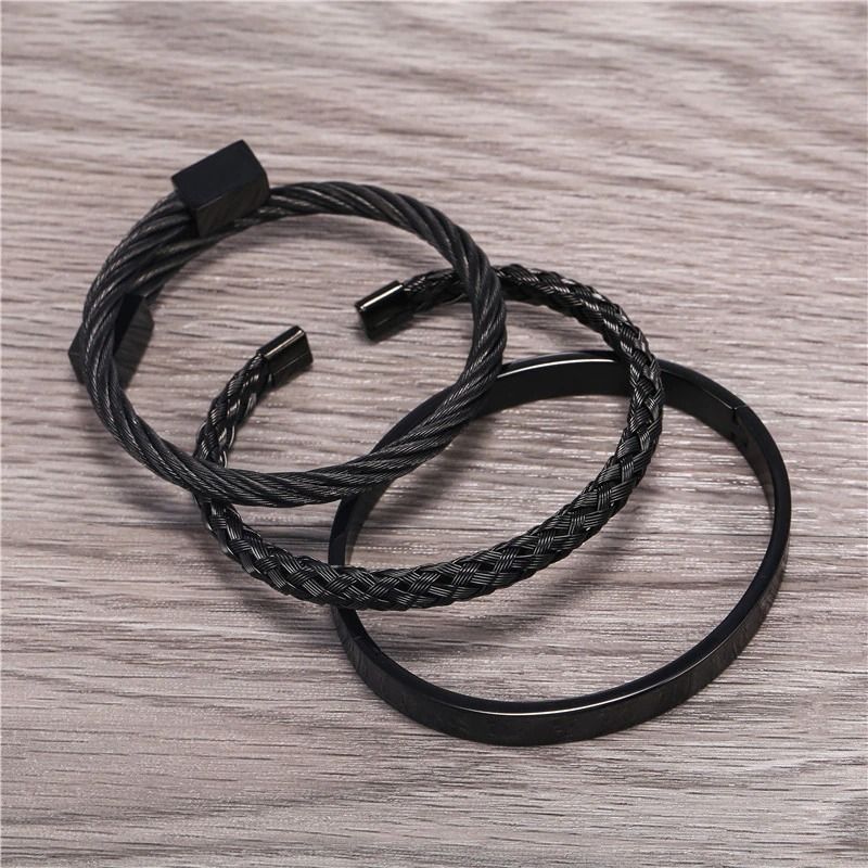 Three elegant black stainless steel and leather bracelets, perfect for a punk style accessory collection.