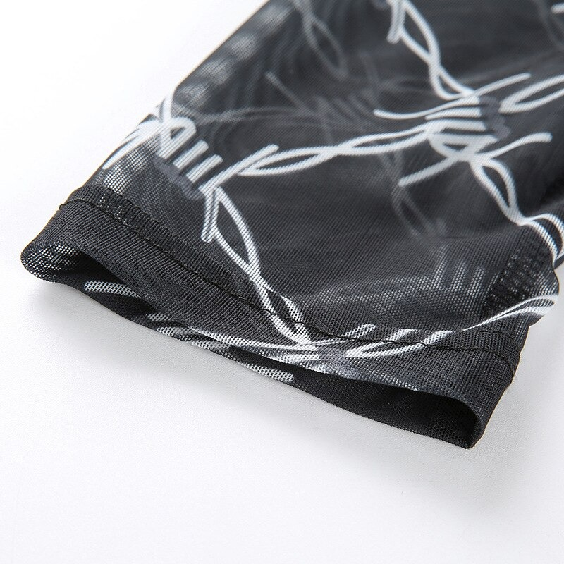 Close-up of black long sleeve crop top with vintage chain print detail, highlighting stylish mesh fabric texture.