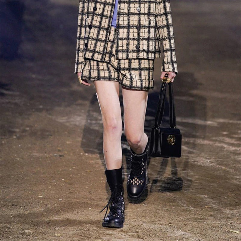 Model showcasing chic plaid outfit with shorts and stylish black lace-up booties, exuding modern street style.