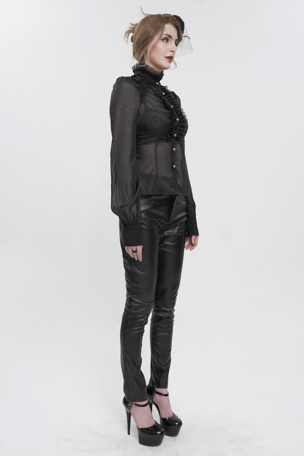 Woman in a sexy gothic black ruffled blouse with long sleeves and fitted pants, showcasing a stylish, elegant look.