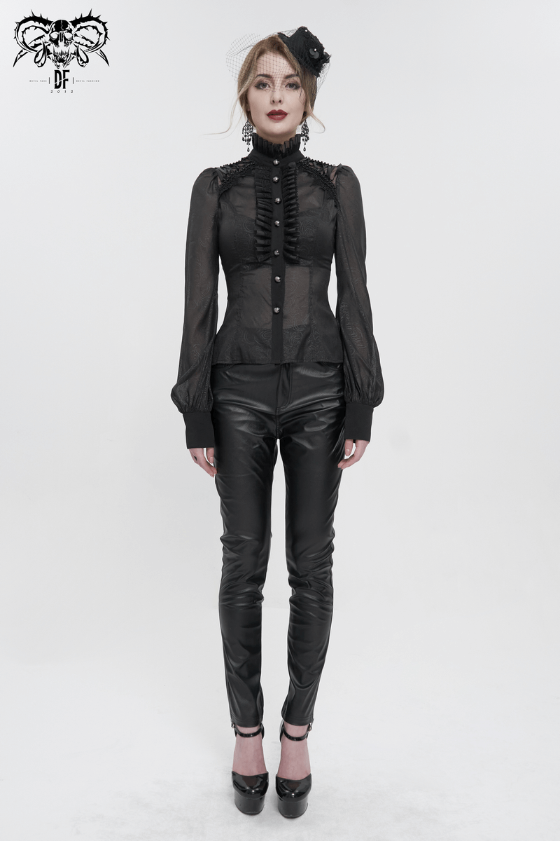 Elegant gothic black long sleeve blouse with ruffles and stand collar modeled by a woman in black pants.