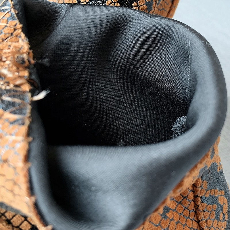Inside view of trendy women's ankle boots with snake skin print and soft black lining.