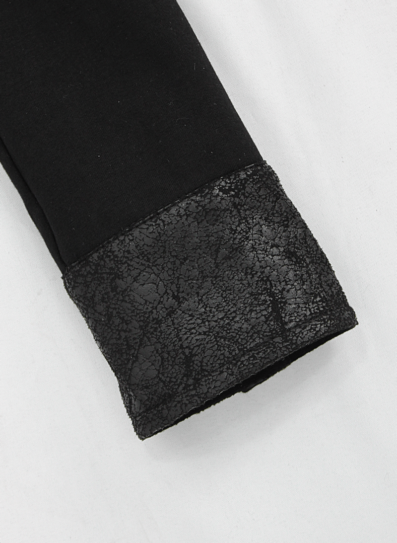 Close-up of a black jumpsuit sleeve featuring a textured lace-like cuff for a stylish gothic look.