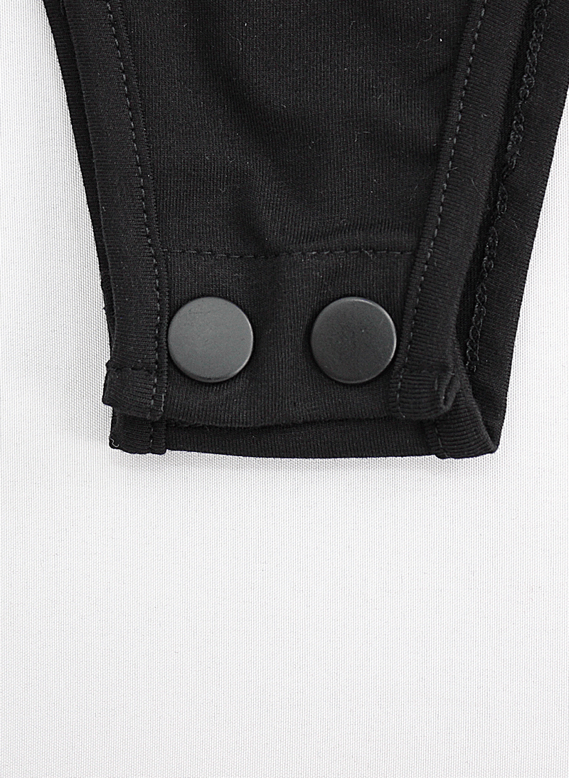 Close-up of black bodysuit sleeve detail featuring stylish buttons for trendy gothic fashion.