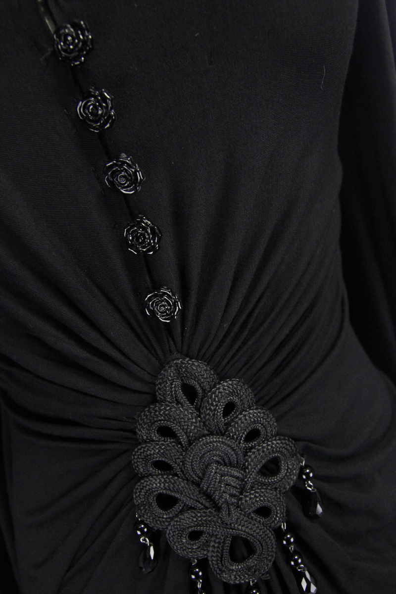 Close-up of elegant black dress detailing, showcasing roses and unique braided embellishments for a gothic style.