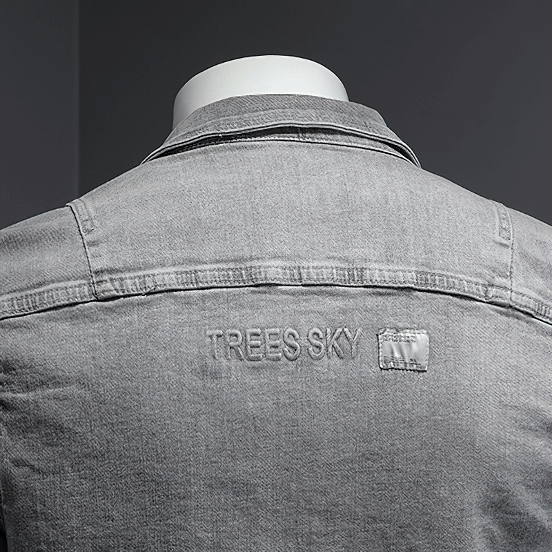 Men's gray denim jacket back view with 'TREES SKY' embroidery on the collar, showcasing casual style.